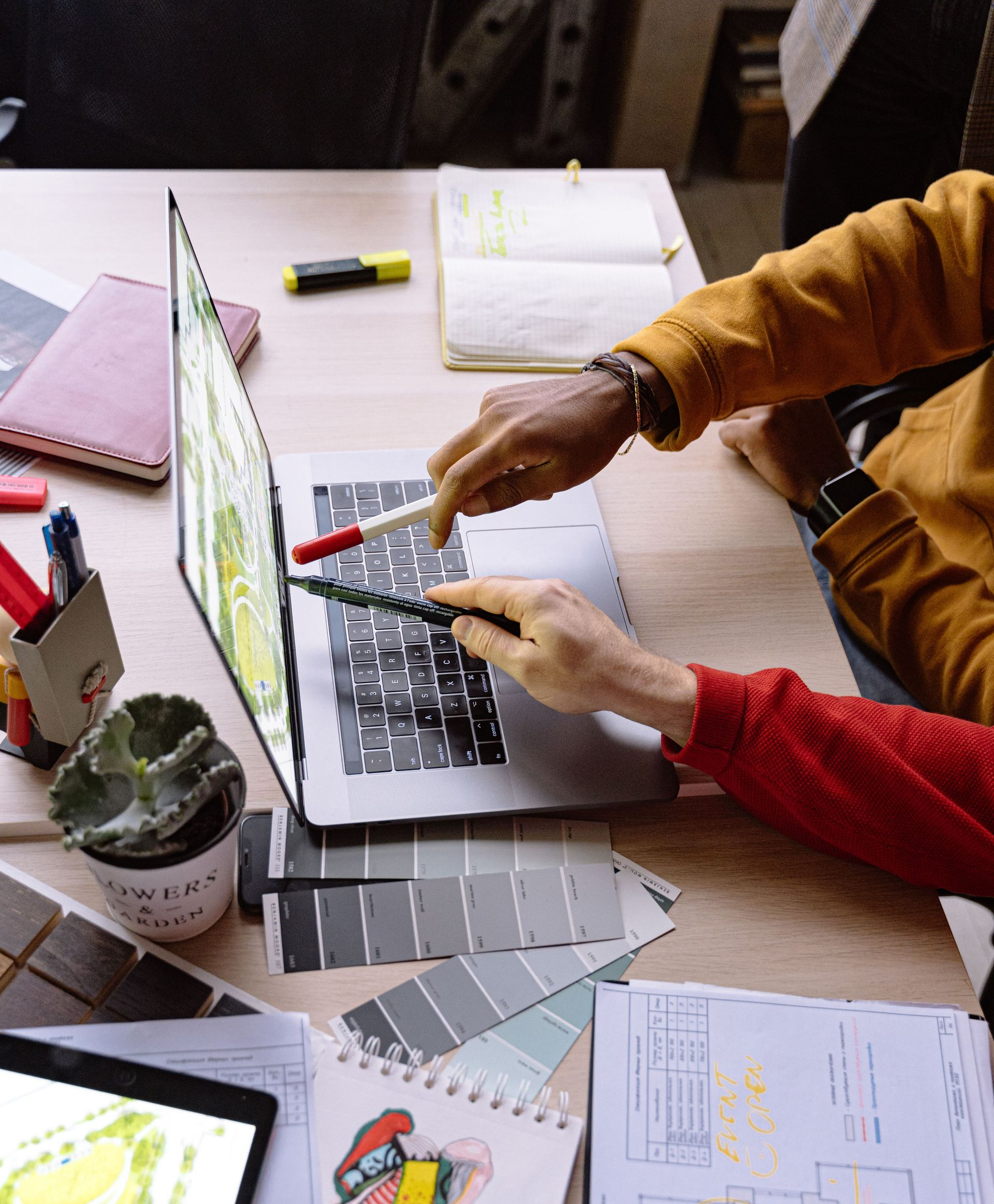 Hands working on a laptop at a desk with notebooks, calculator, and papers in a study workspace