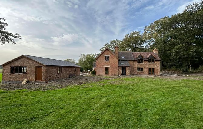 A large brick house is sitting in the middle of a lush green field.