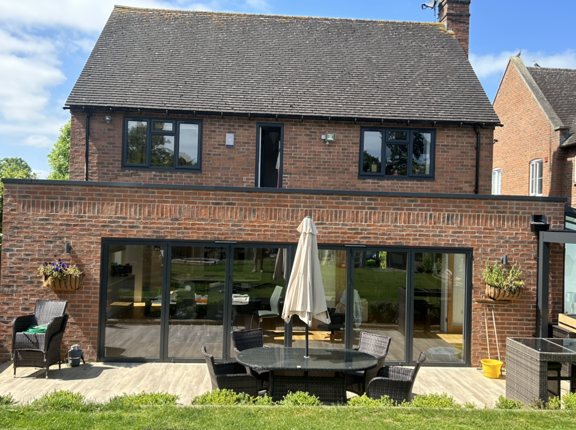 A large brick house with a patio area and a table and chairs in front of it.