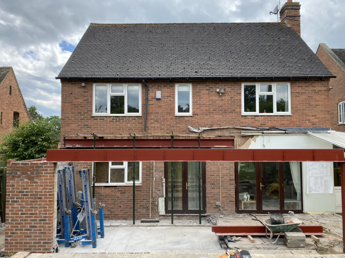 The back of a brick house with a roof that is being built.