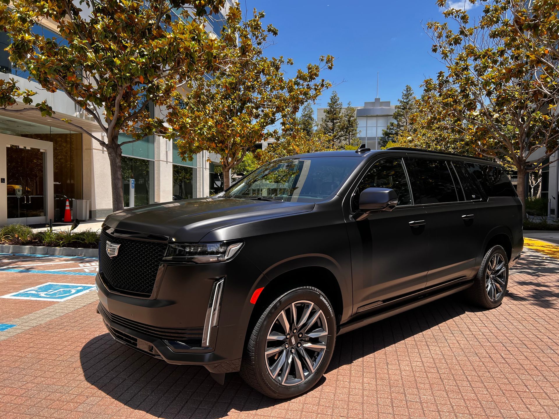 A black cadillac escalade is parked in a parking lot in front of a building.