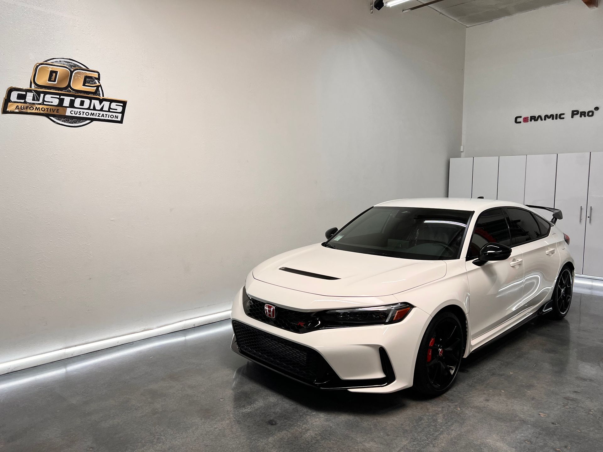 A white honda civic is parked in a garage.