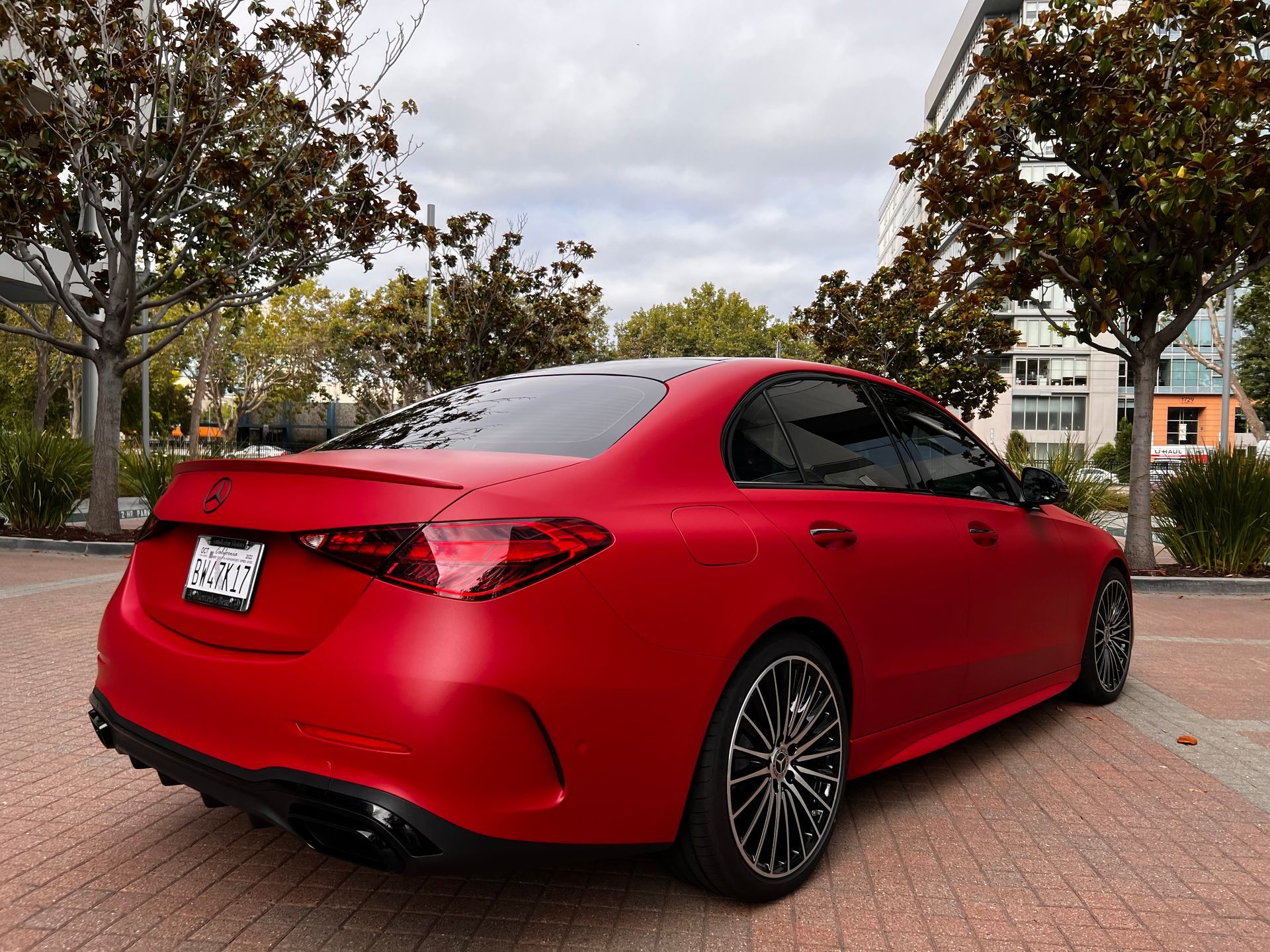 A red mercedes benz is parked in a parking lot