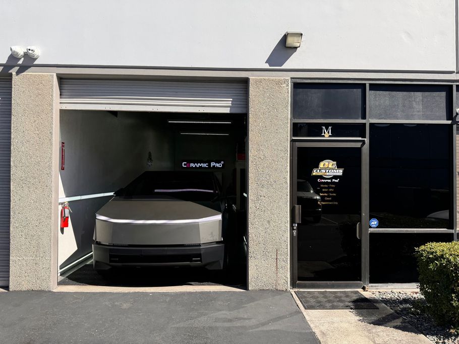 A silver car is parked in a garage next to a building
