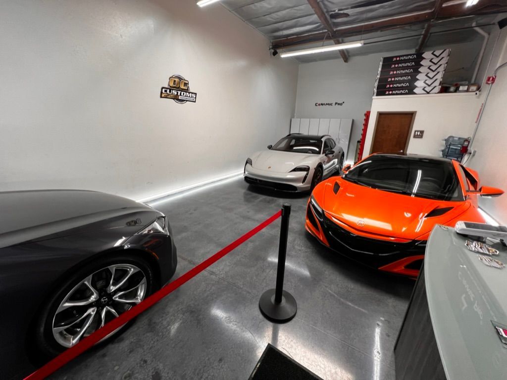 Three cars are parked in a garage behind a red barrier.