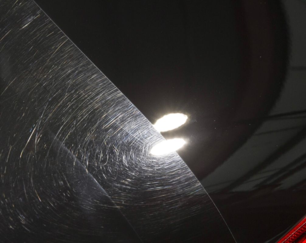 A close up of a black car with scratches on it