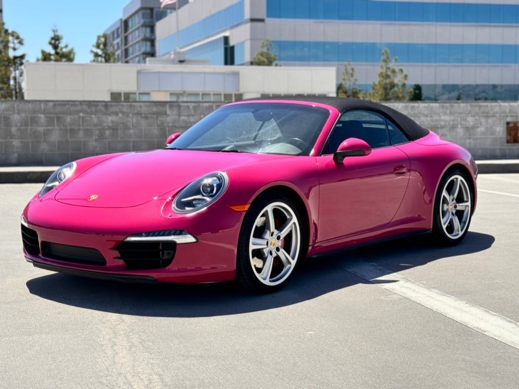 A pink porsche is parked in a parking lot