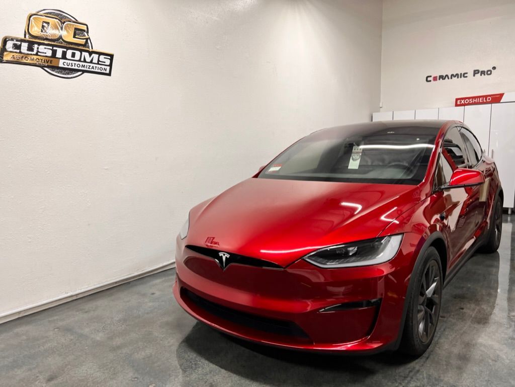 A red tesla model x is parked in a garage.