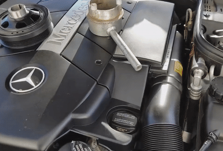 A close up of a mercedes engine with a wrench on it