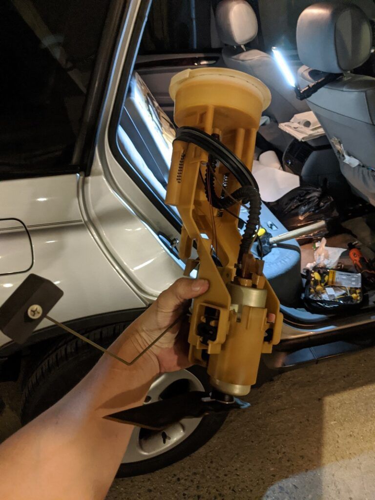 A person is holding a fuel pump in front of a car.