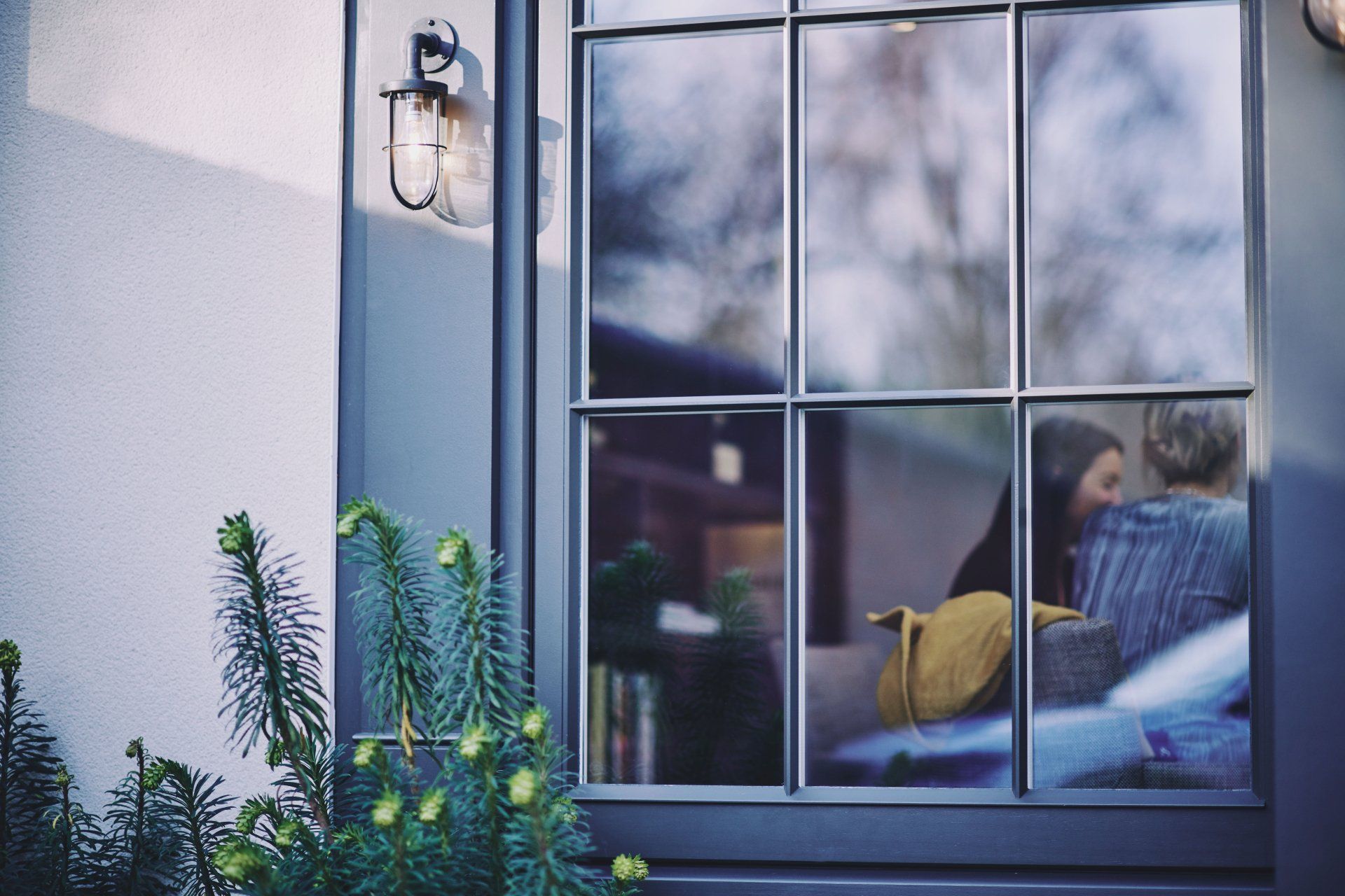 A woman is sitting on a couch looking out of a window.