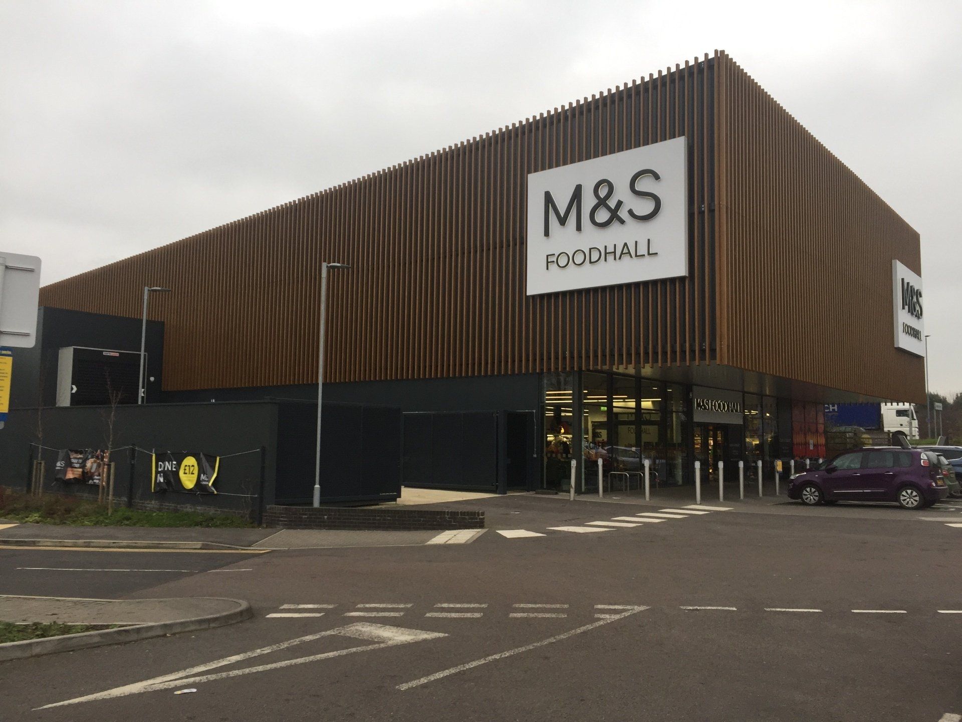 A m & s store with a car parked in front of it