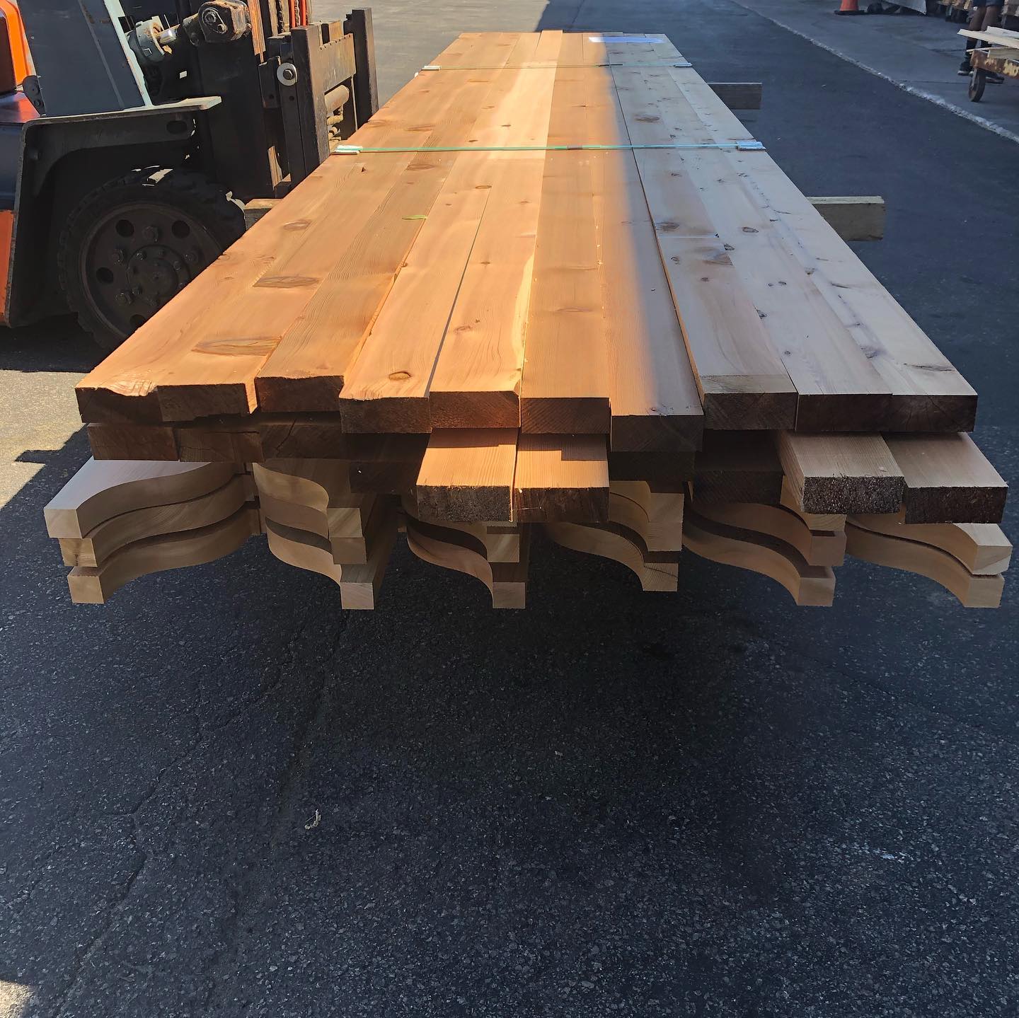 A forklift is carrying a large stack of wood