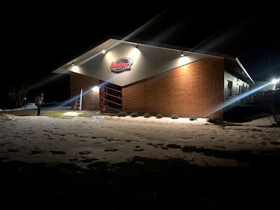Car wash building at night with a car logo. Snow on the ground. | Dave Muller Automotive & Trailer
