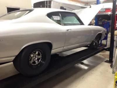 White muscle car on a lift with the hood open, inside a garage. | Dave Muller Automotive & Trailer