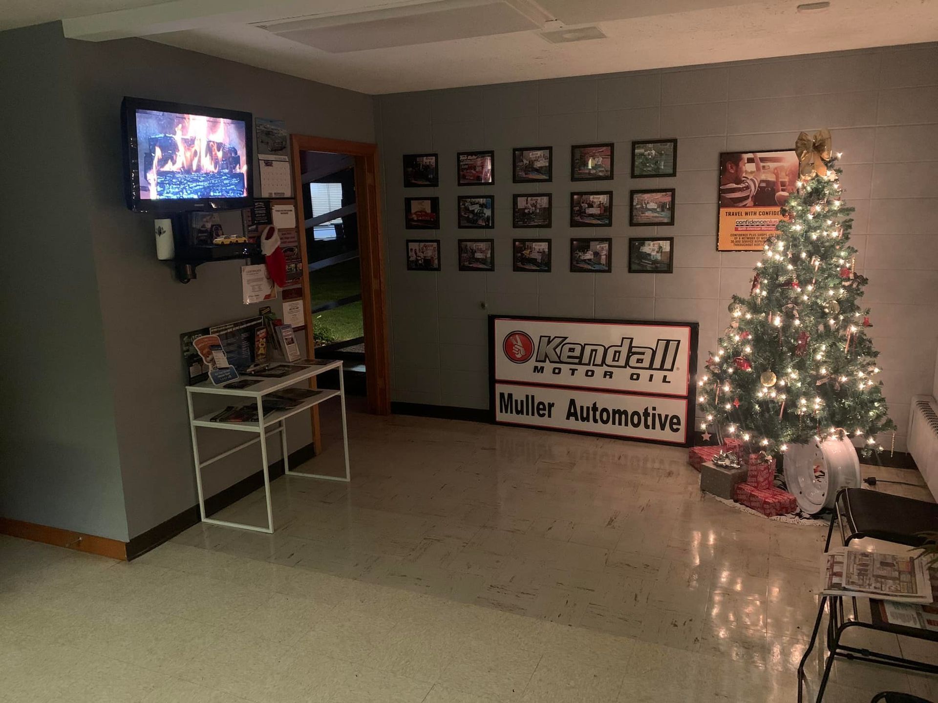 A waiting room with a TV, framed photos, a Christmas tree, and a Kendall oil sign. | Dave Muller Automotive & Trailer