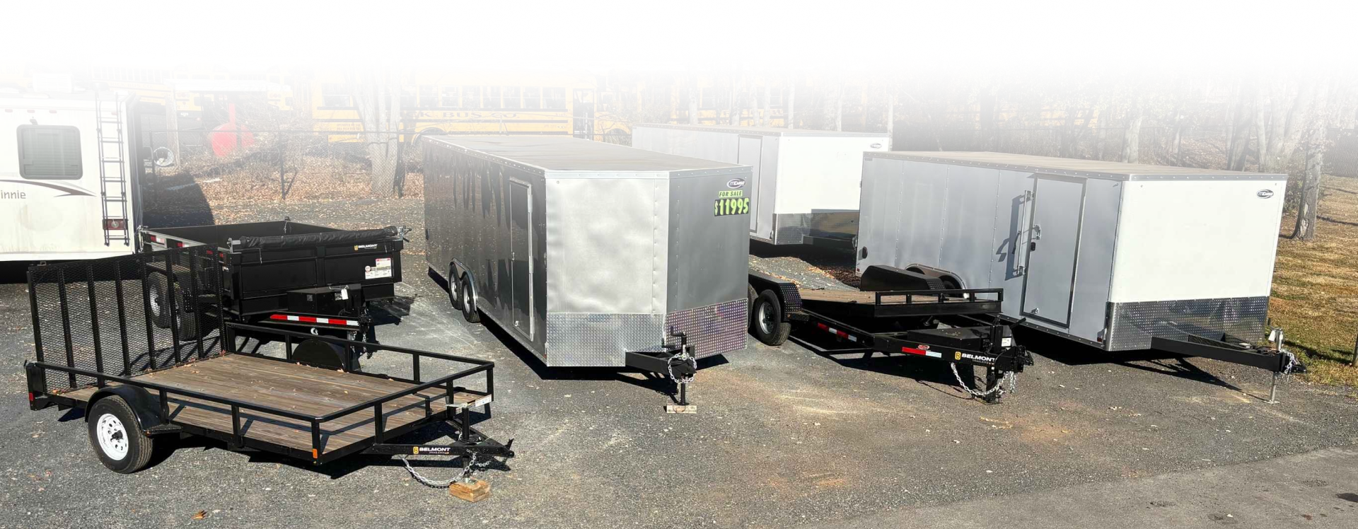 Cargo trailers parked on gravel, with black and gray utility trailers in a lot | Dave Muller Automotive & Trailer