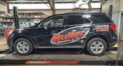 Black SUV with business logo on a lift in a garage. | Dave Muller Automotive & Trailer