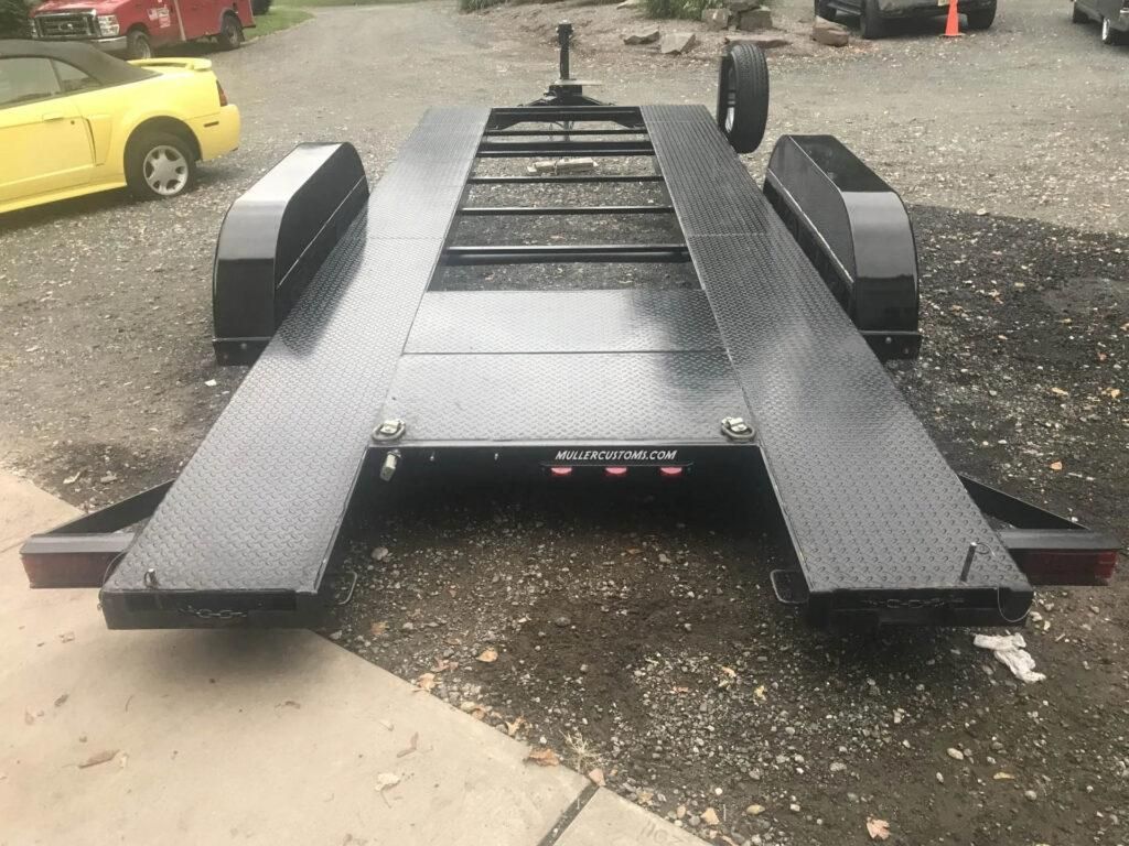 Black car hauler trailer parked on asphalt, angled shot. | Dave Muller Automotive & Trailer