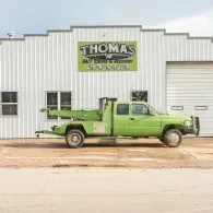 Green tow truck parked in front of a white building with