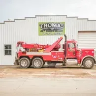 Red tow truck parked in front of a white building with