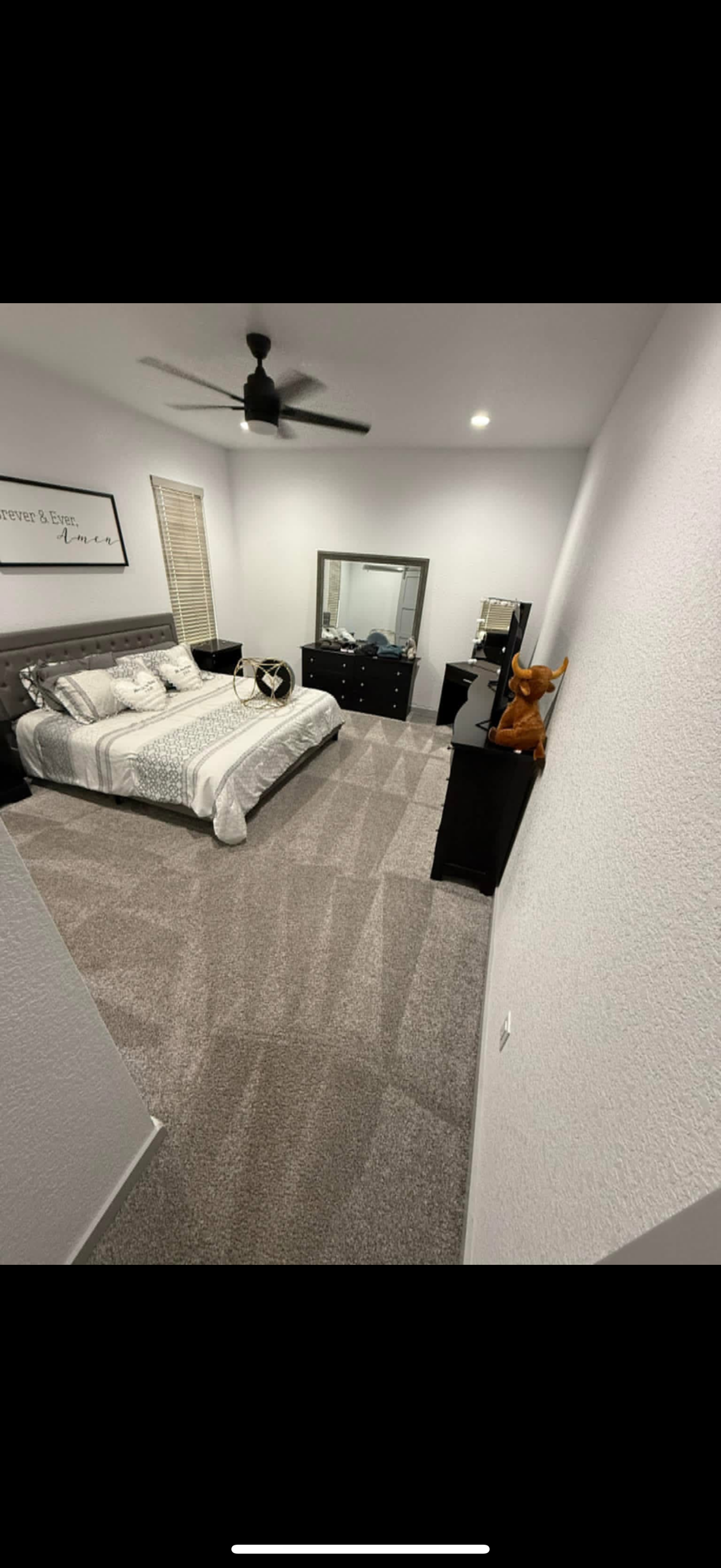 A bedroom with two beds , a dresser , a mirror and a ceiling fan.