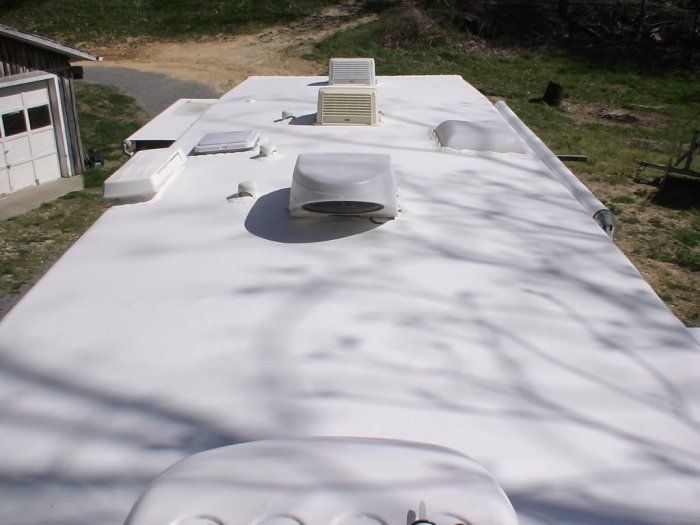 The roof of a white rv has a few vents on it