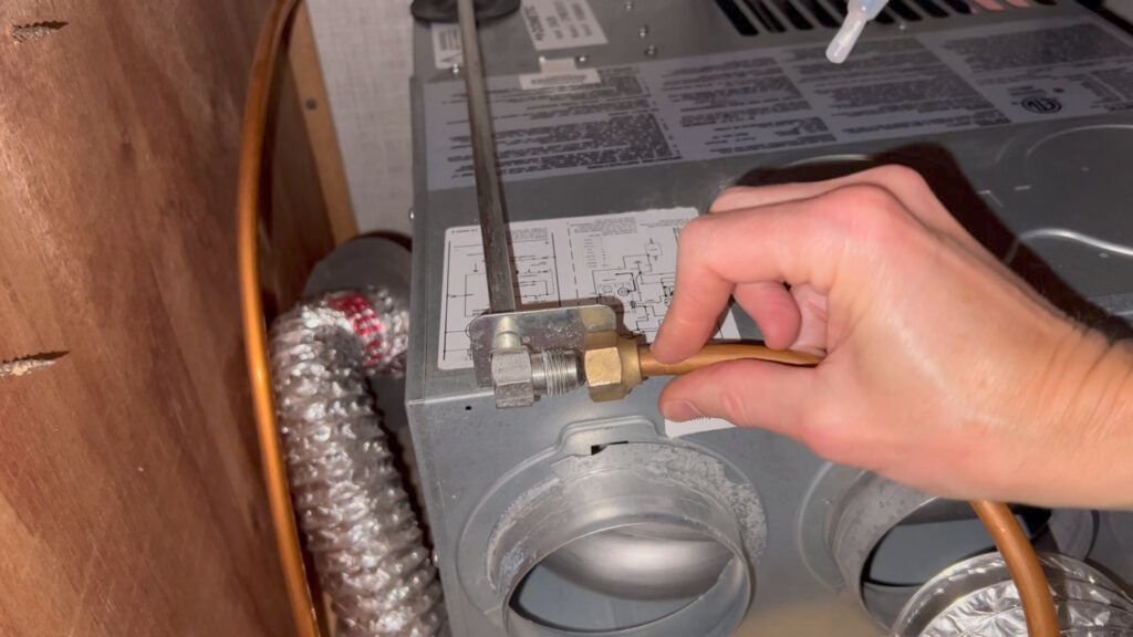 A person is holding a copper pipe in front of an air conditioner.