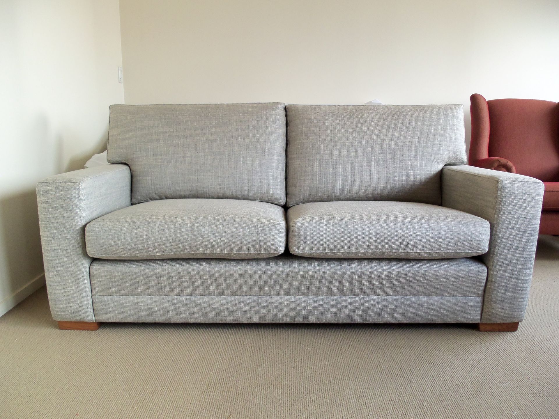 A grey couch is sitting in a living room next to a red chair