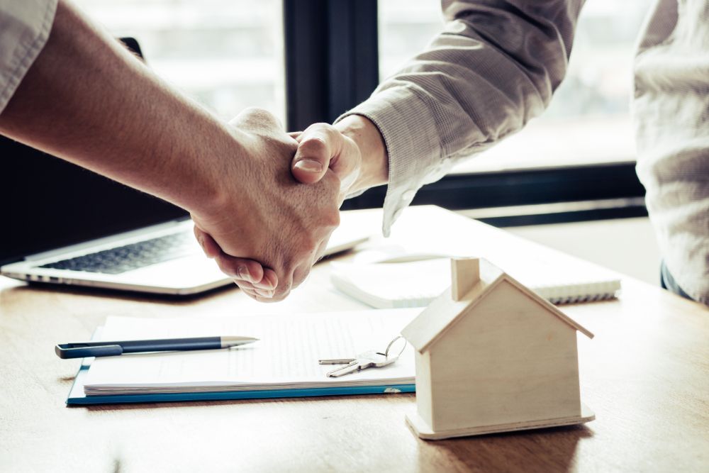 Two People Are Shaking Hands Over a Table — Licensed Conveyancing Agent in Fannie Bay, NT