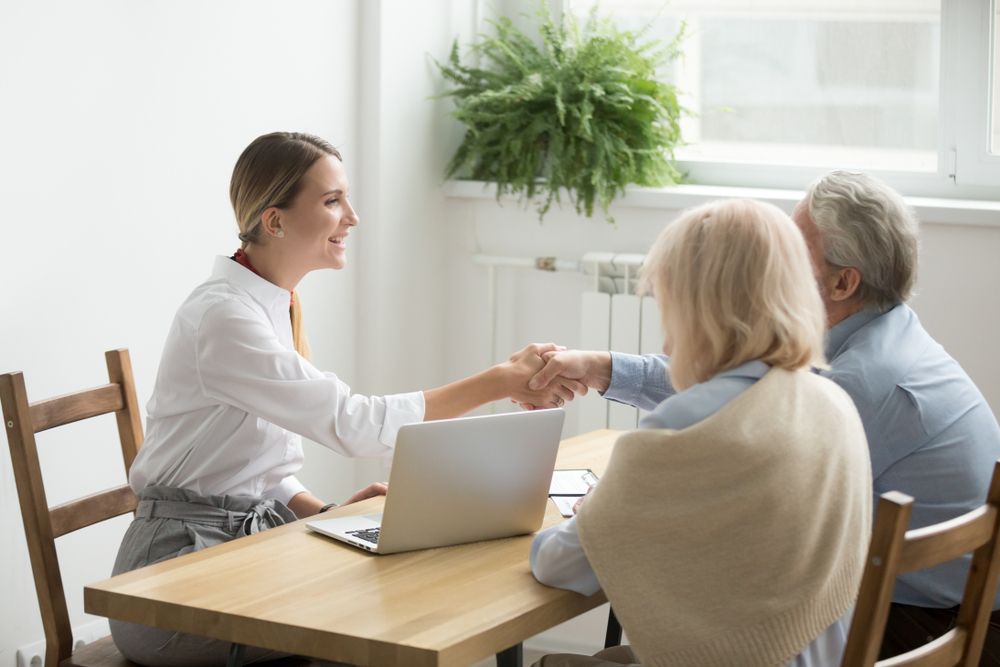A Joyful Woman Engaging in a Handshake With an Elderly Senior Couple — Licensed Conveyancing Agent in Fannie Bay, NT