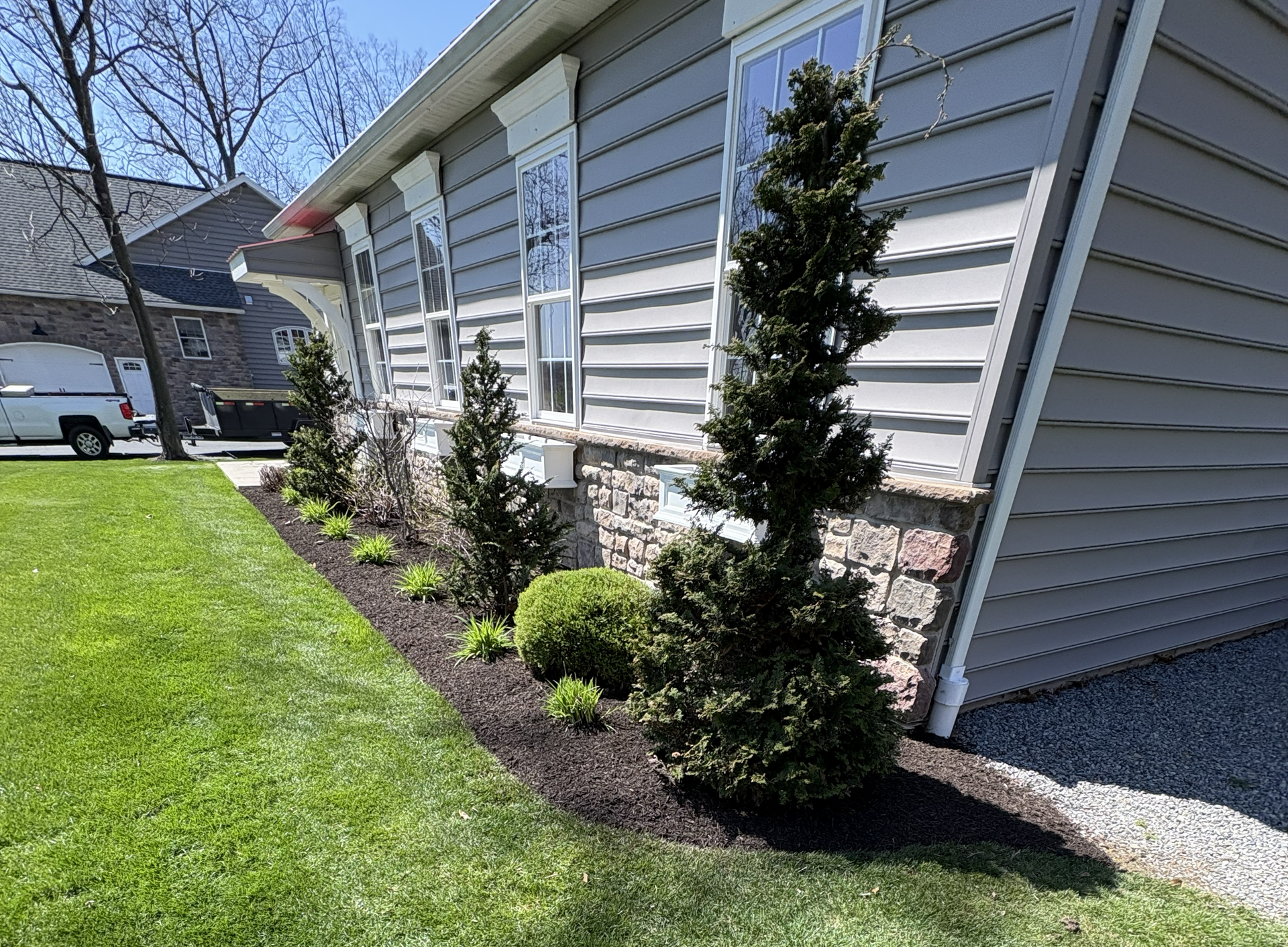 Suburban house side yard with newly landscaped shrubs and mulch along the foundation