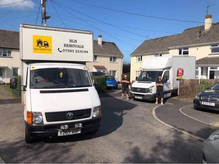 Two white vans on a residential street; one has a removal company sign.