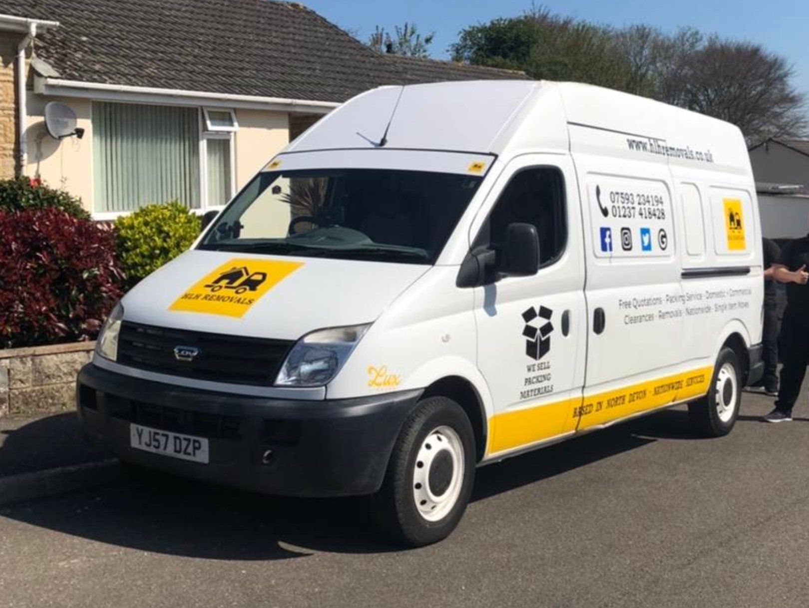 White delivery van with yellow and black branding parked on a residential street