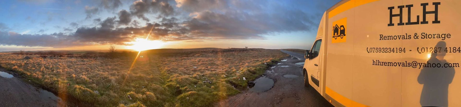 Sunrise over a rocky coastline beside a beige wall with “HLH” text on the right