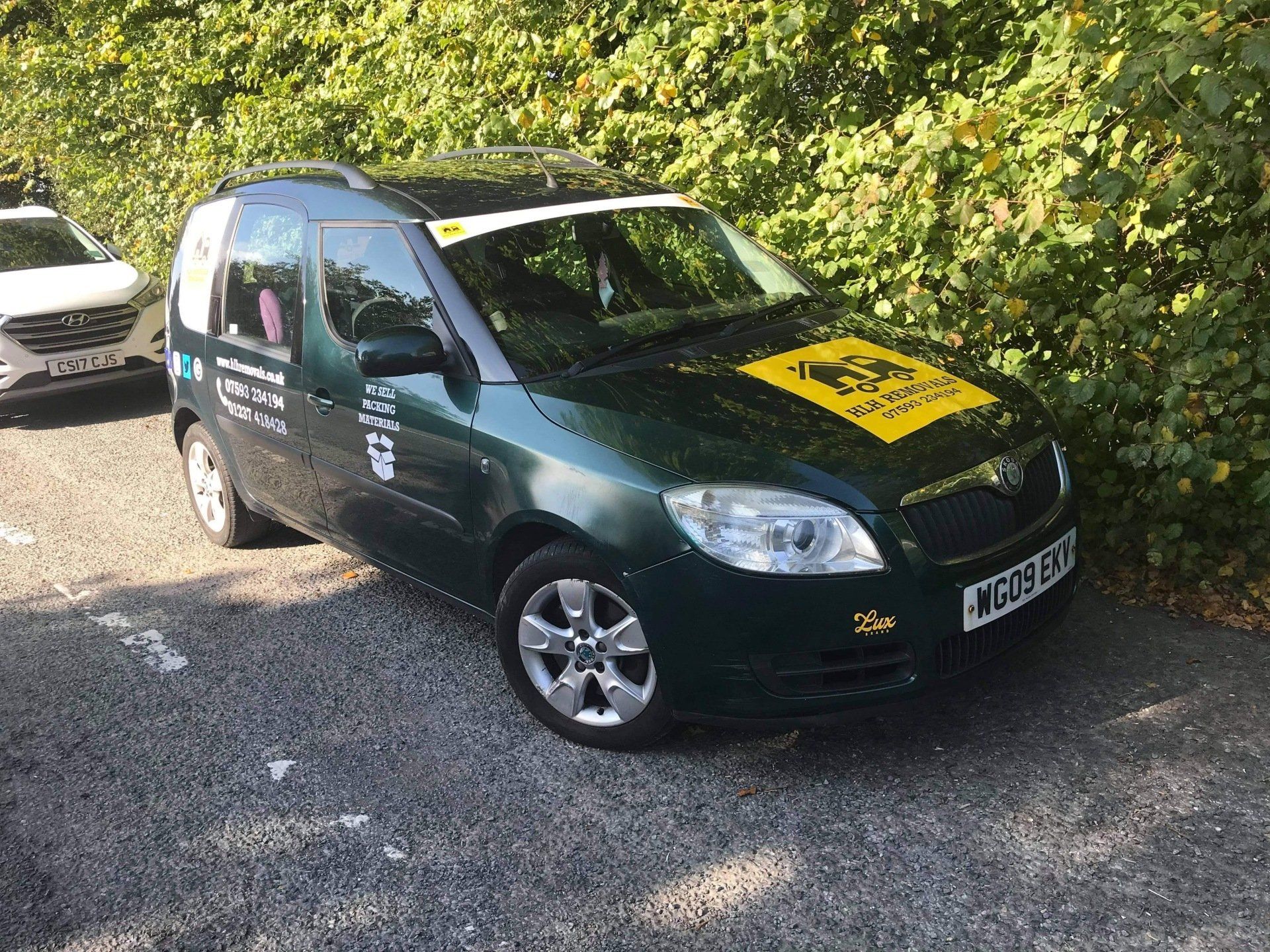 Green promotional van parked on gravel with a yellow logo on the hood and side decals