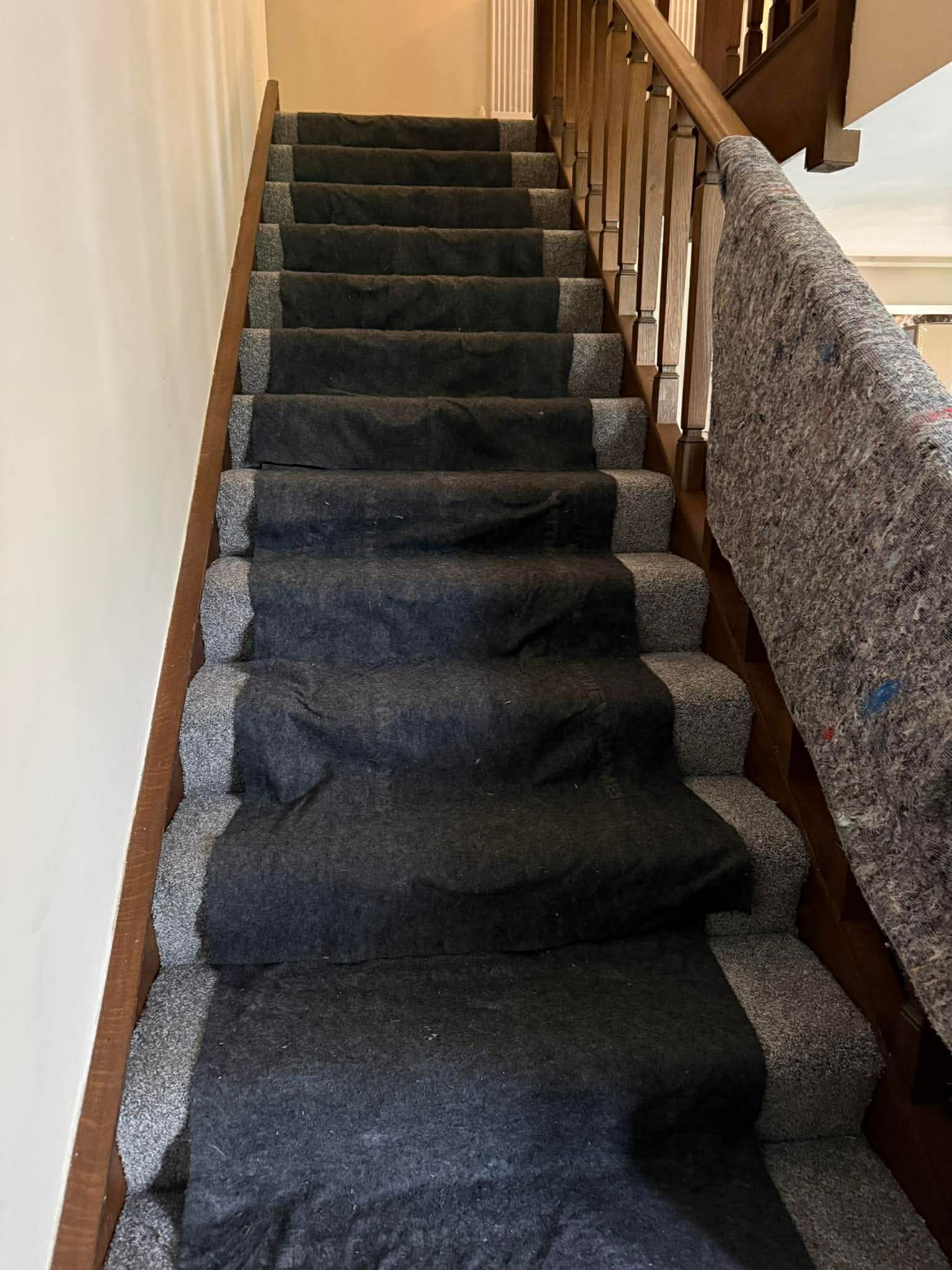 Carpeted indoor staircase with wooden banister and stone-textured wall, viewed from the bottom up