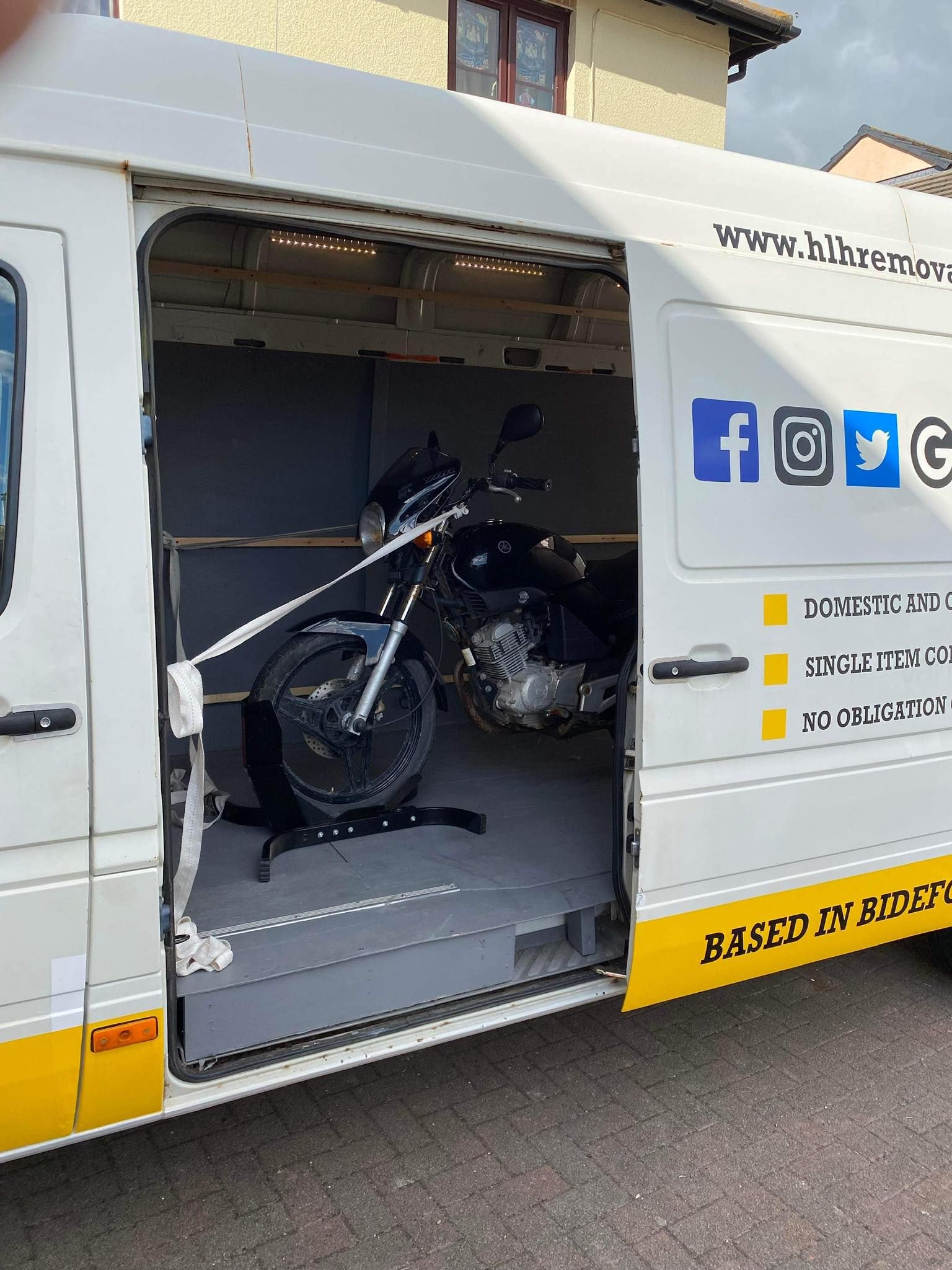 Black motorcycle loaded inside an open white transport van