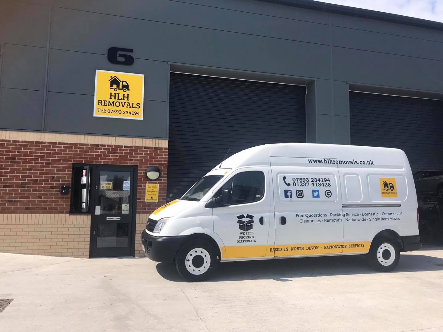 White delivery van parked outside a brick building with a yellow sign and dark doorway.
