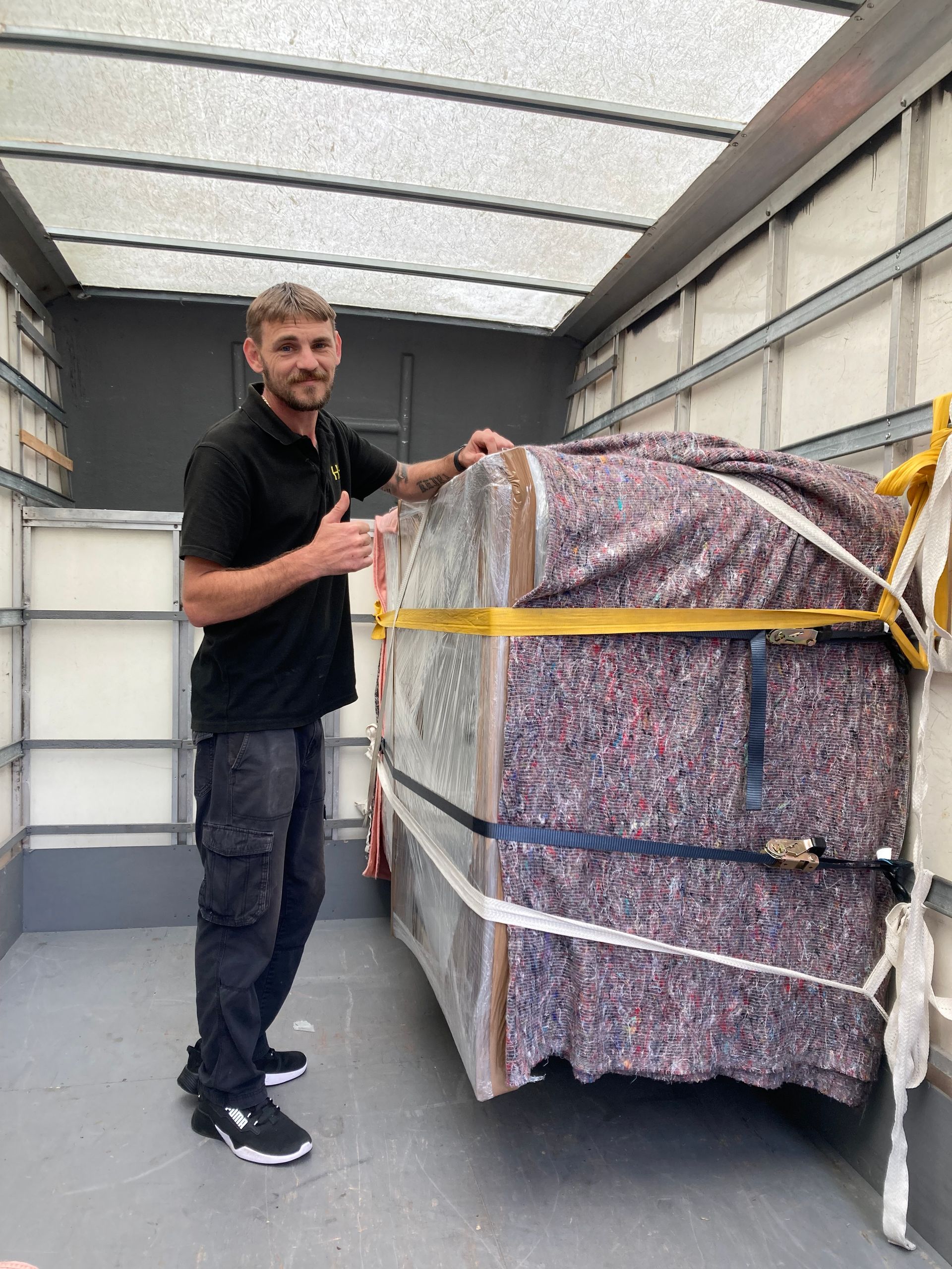 Man standing beside a strapped, wrapped pallet inside a box truck