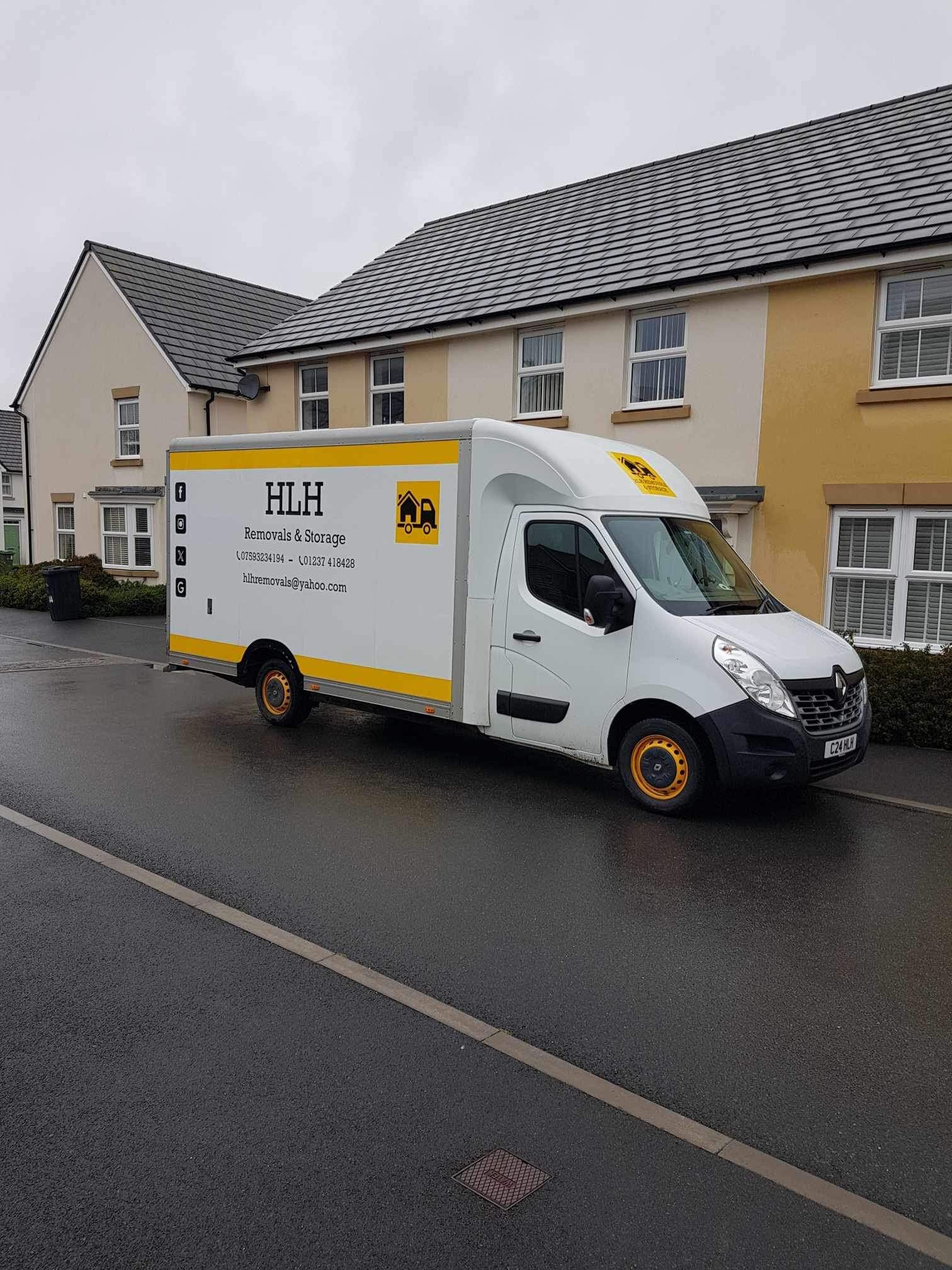 White delivery van parked on a wet residential street beside beige houses on a rainy day
