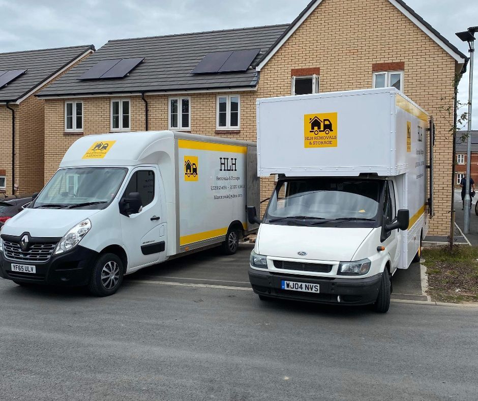 Two white delivery vans parked outside brick houses on a suburban street.