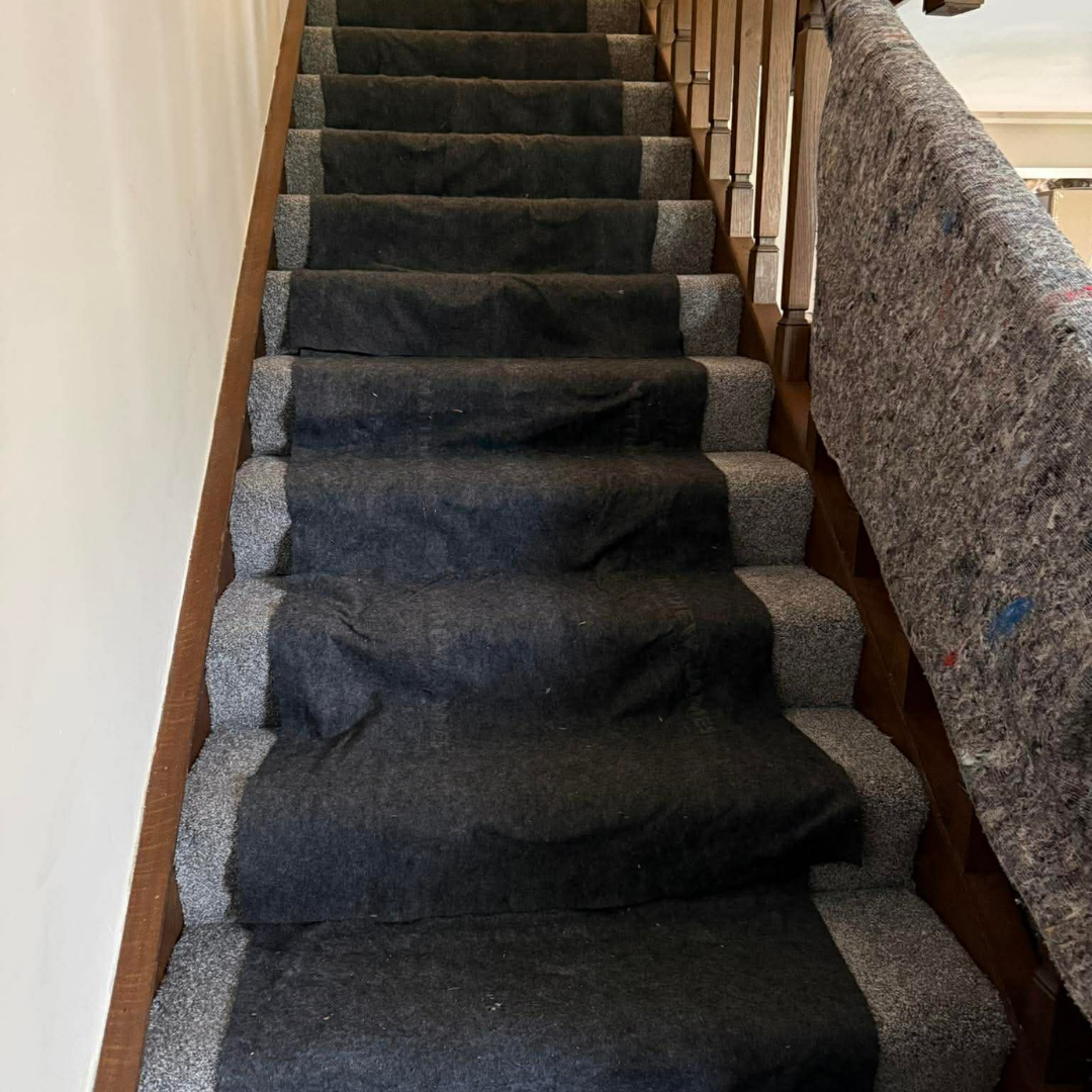 Carpeted staircase with dark runner and wooden banister in a narrow hallway
