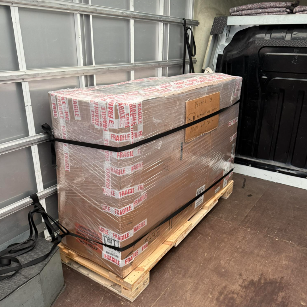 Pallet of wrapped boxes strapped in a cargo van’s open rear area