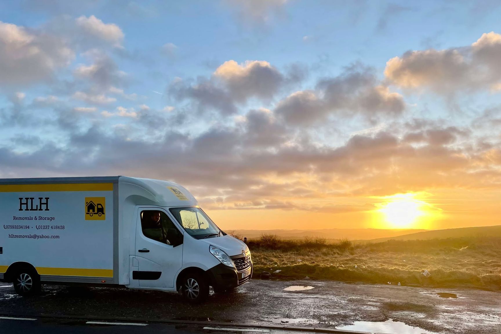 White delivery van parked by the sea at sunset with glowing sky and wet shoreline