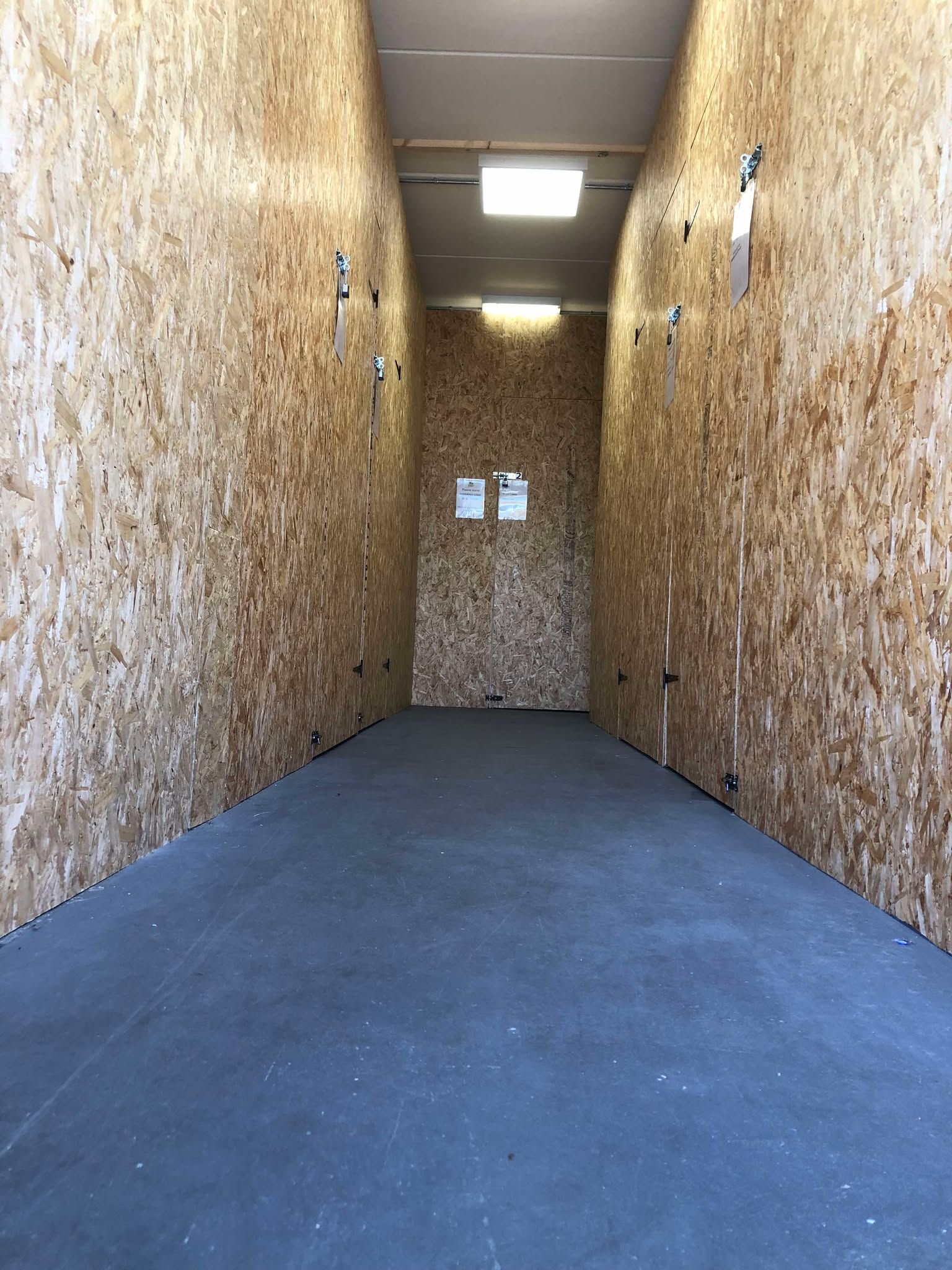 Narrow carpeted hallway with wood-paneled walls and a fluorescent ceiling light