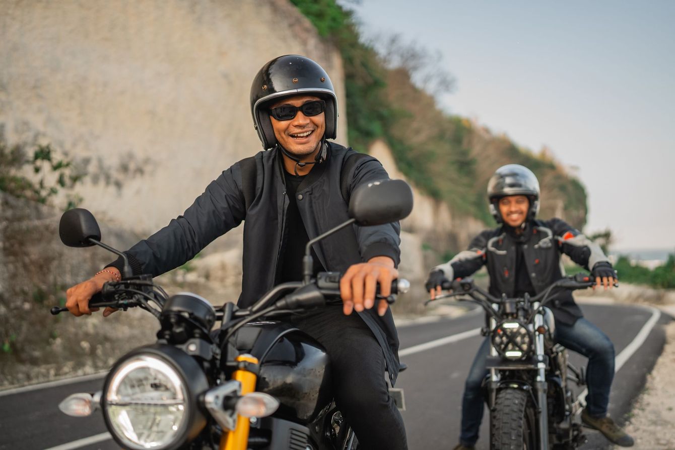 Two men are riding motorcycles down a road.
