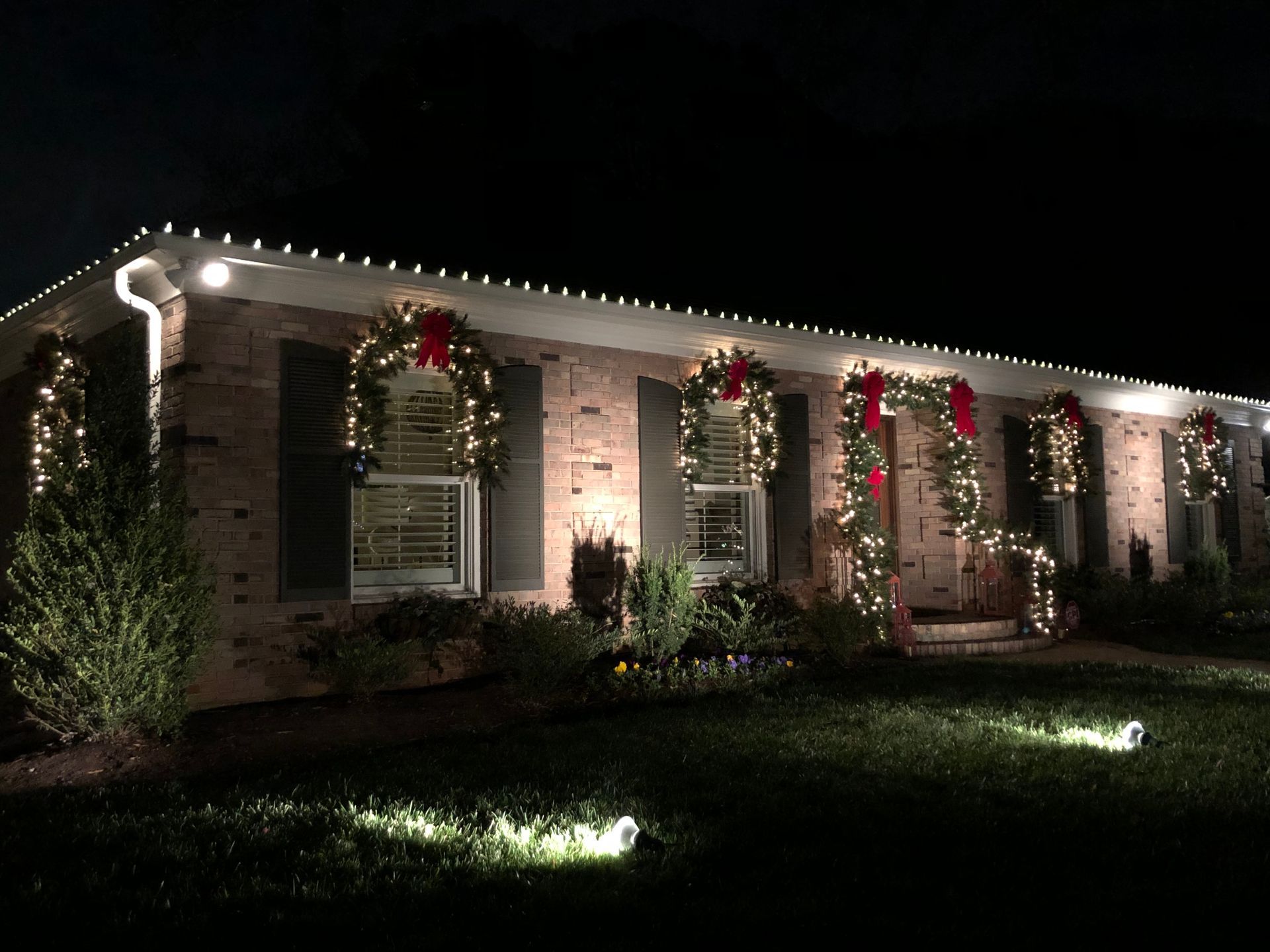 House decorated with Christmas lights and wreaths at night.