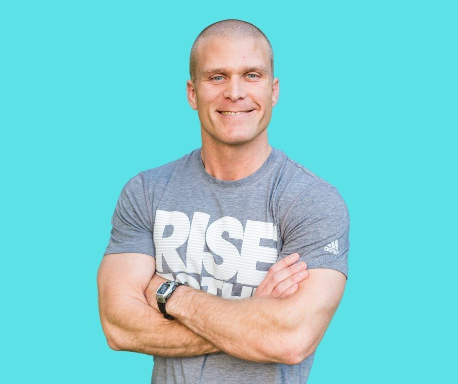Smiling man with crossed arms in a gray shirt against a turquoise background