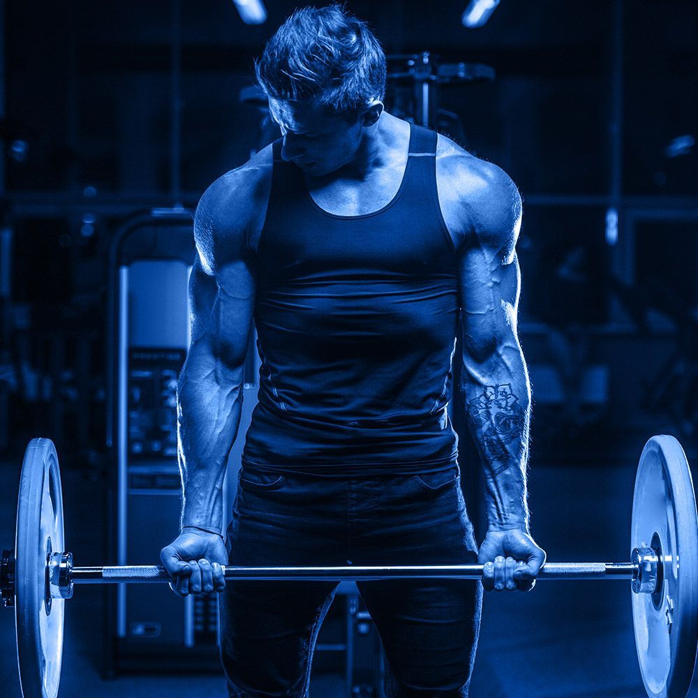 A man is lifting a barbell in a gym.